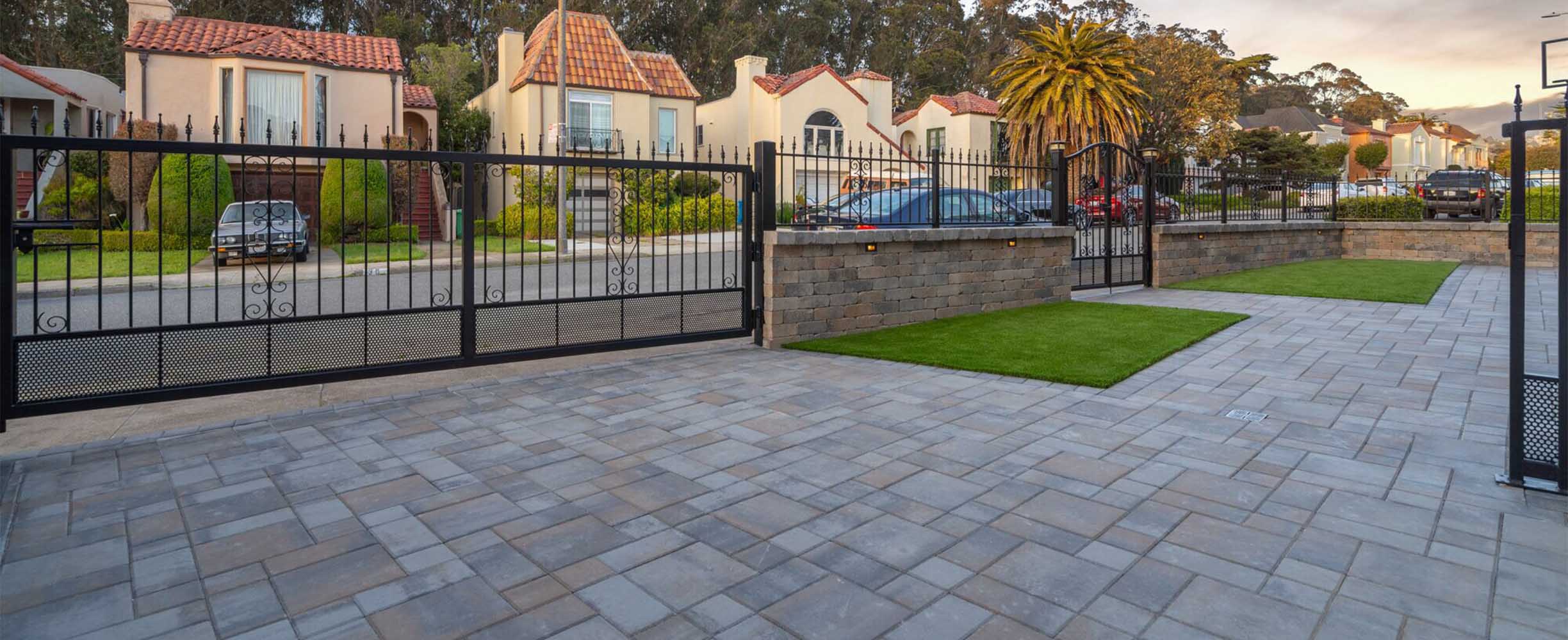 Landscaping with stone car entry and patio, fence and iron gates.