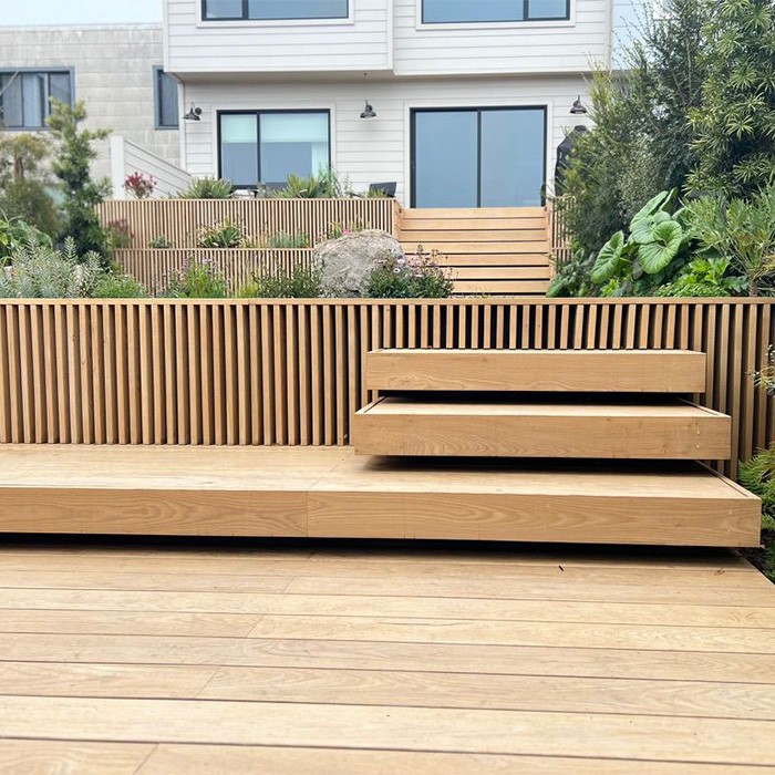 A residential landscaping project including a modern wooden bench and terrace.