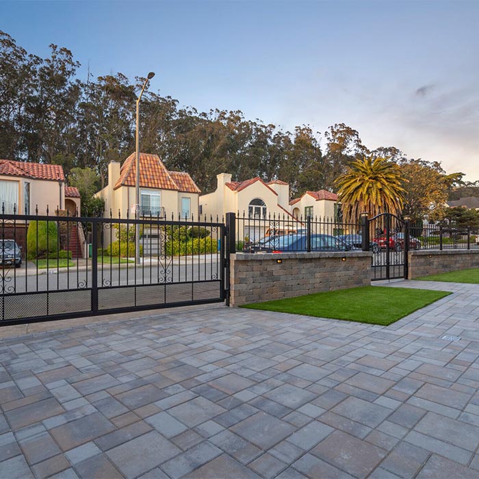 A residential landscaping project including a large stone pathway and patio, as well as a beautiful iron fence.